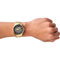 Goldene Armani Exchange Herrenuhr am Handgelenk, mit schwarzem Zifferblatt und skelettiertem Design
 - Bild 5