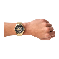 Goldene Armani Exchange Herrenuhr am Handgelenk, mit schwarzem Zifferblatt und skelettiertem Design