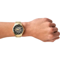 Goldene Armani Exchange Herrenuhr am Handgelenk, mit schwarzem Zifferblatt und skelettiertem Design